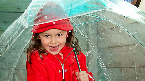 Kleines Mädchen lachend unter einem Regenschirm