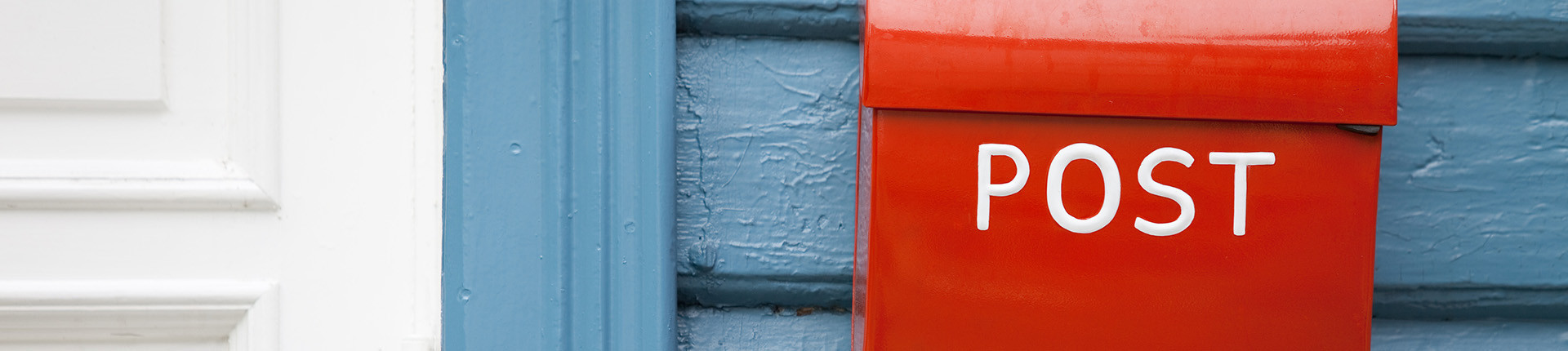 roter Briefkasten an blauer Holzwand