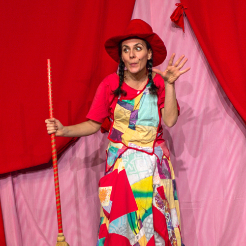 Schauspielerin als Hexe verkleidet mit Hexenbesen und Hexenhut auf dem Kopf