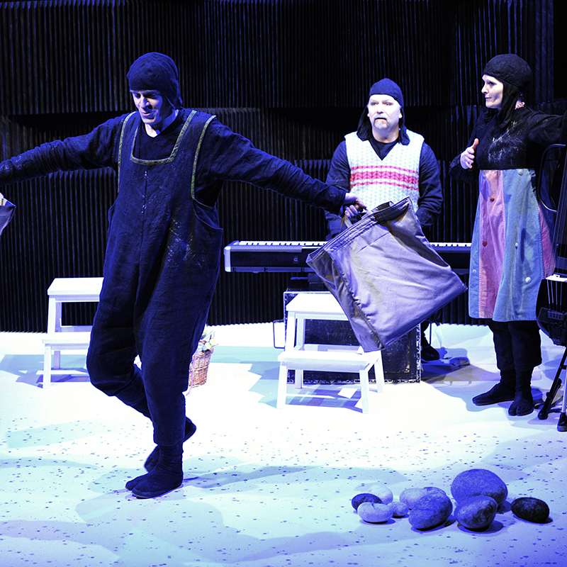 Theaterfoto: 3 Schauspieler mit Mütze auf der Bühne in kaltem Licht