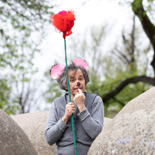 Schauspieler als Maus verkleidet mit gebastelter Blüte in der Hand
