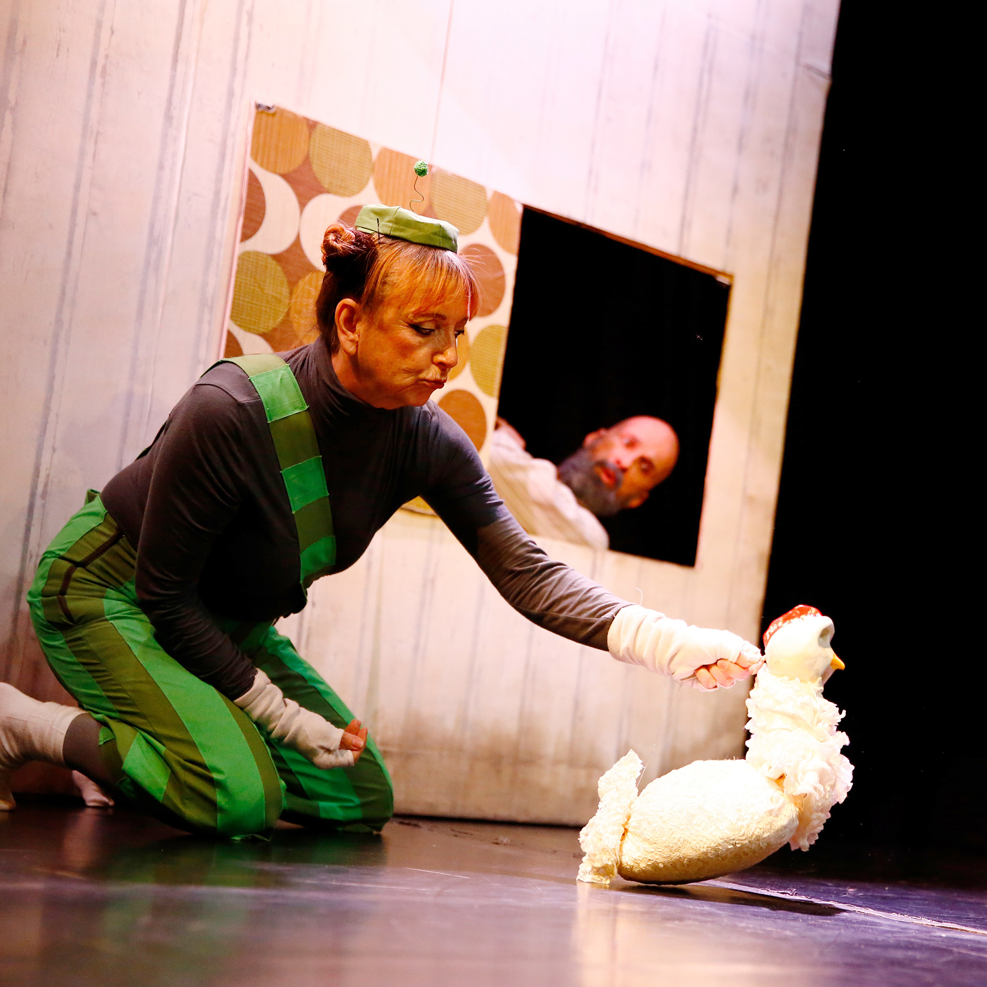 Theaterfoto: Schaupielerin im Finduskostüm hält ein Puppen-Huhn in der Hand
