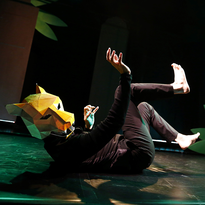 Theaterfoto: Schauspieler mit Tigermaske liegt auf der Bühne